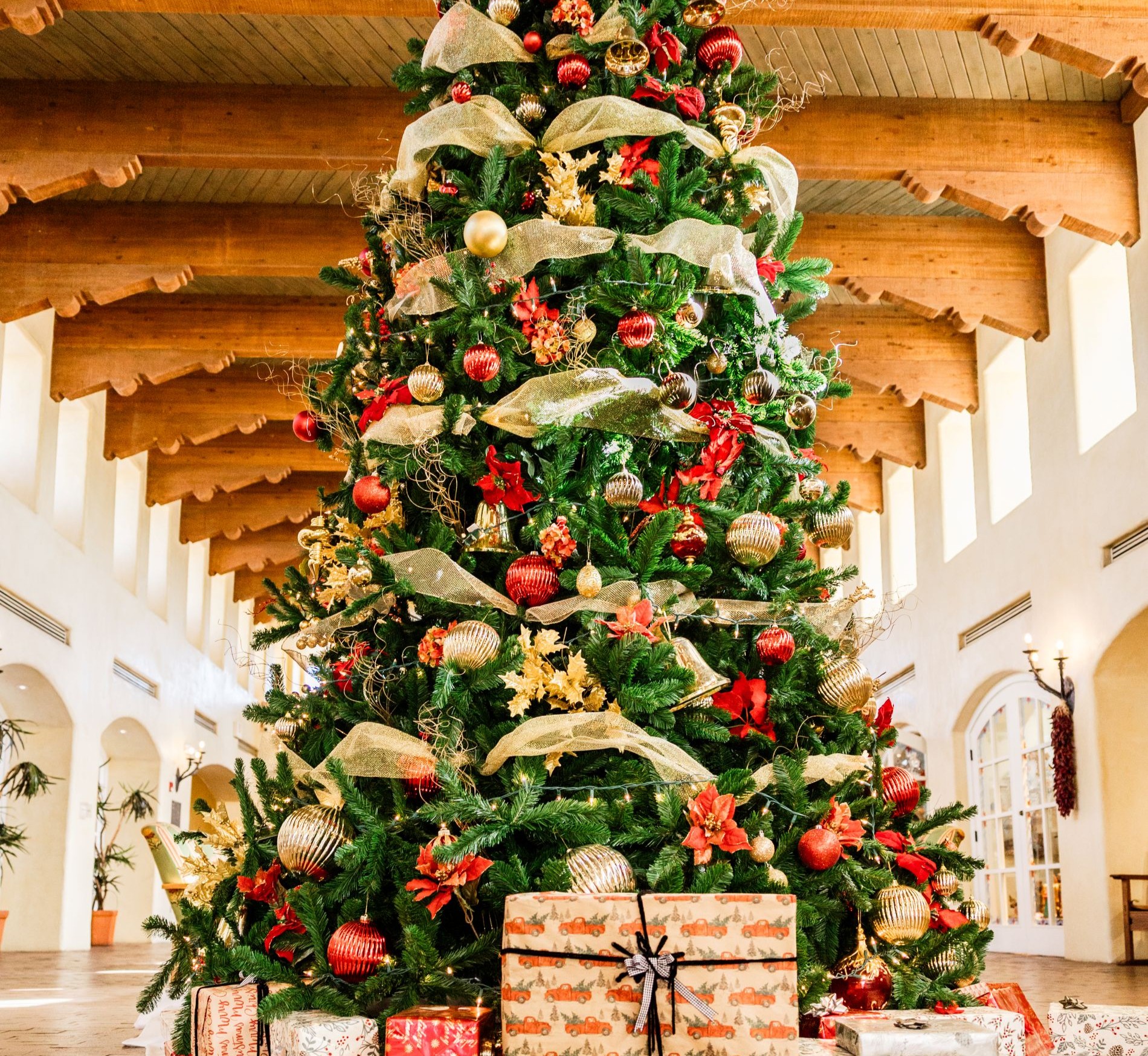 large Christmas tree in lobby decorate with red and gold ornaments and gold ribbon