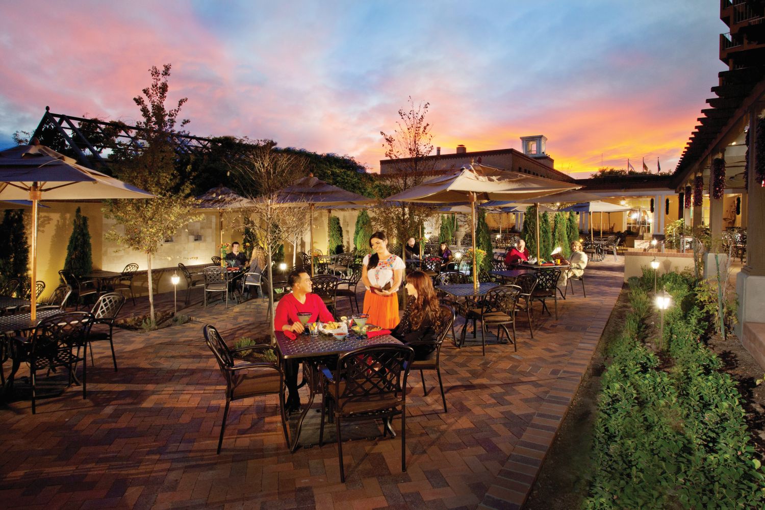Garduno's patio at dusk people sitting at table being served by a woman