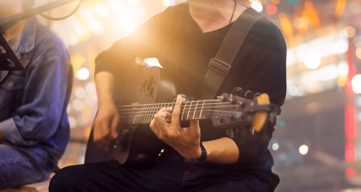 Man on a stage sitting down playing a guitar