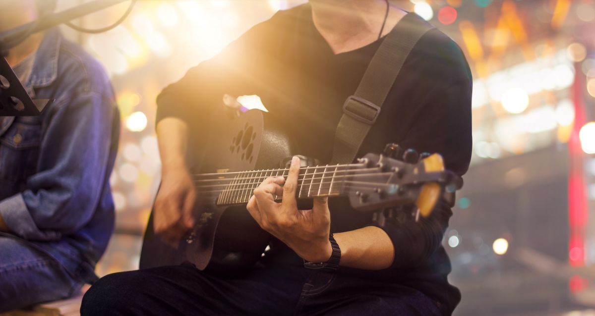 Man on a stage sitting down playing a guitar