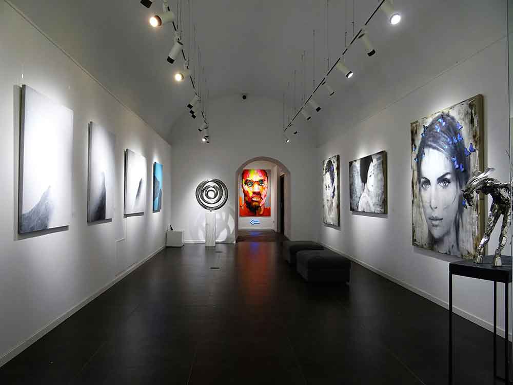 Modern art gallery with portrait paintings and sculptures.
