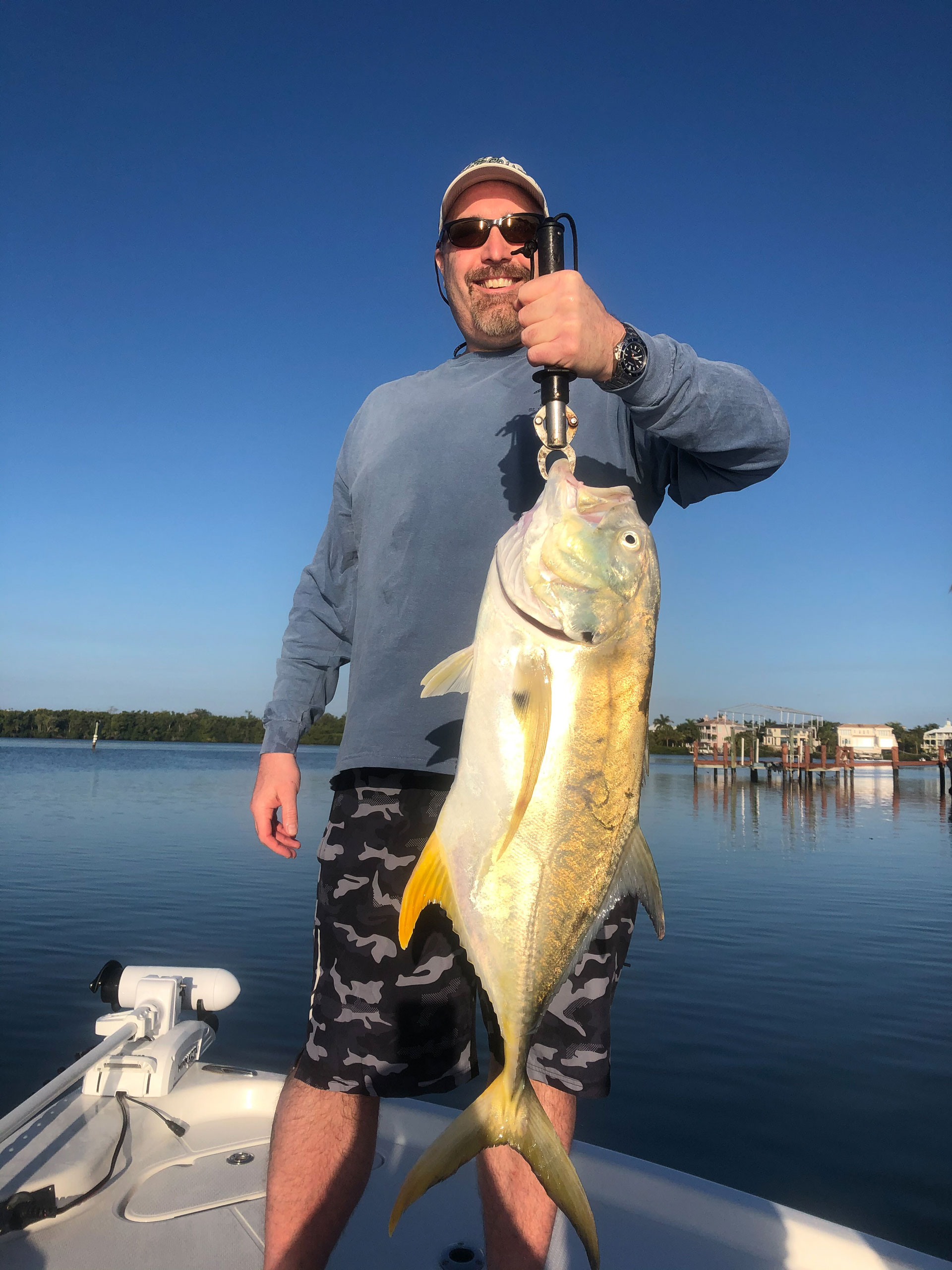 Man holding a large fish while standing on a boat.