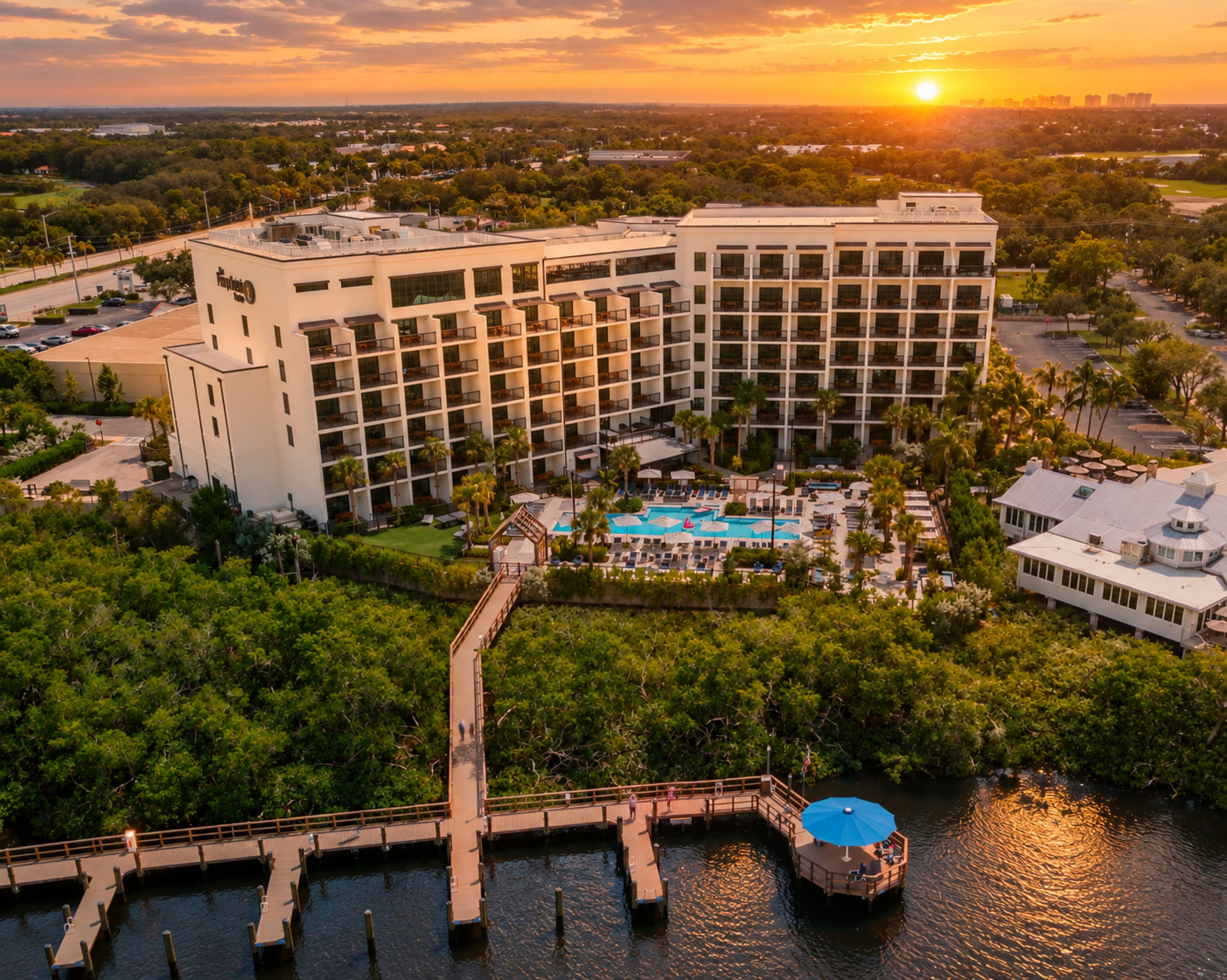 1. Aerial view of a waterfront hotel, pool, and docks at sunset.