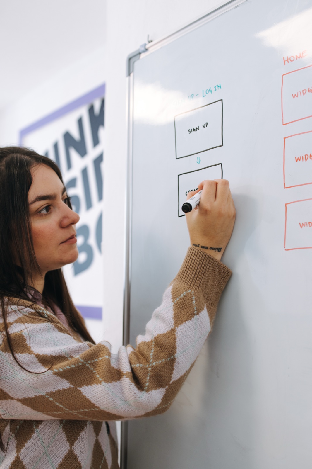 A designer sketching a user flow on a whiteboard