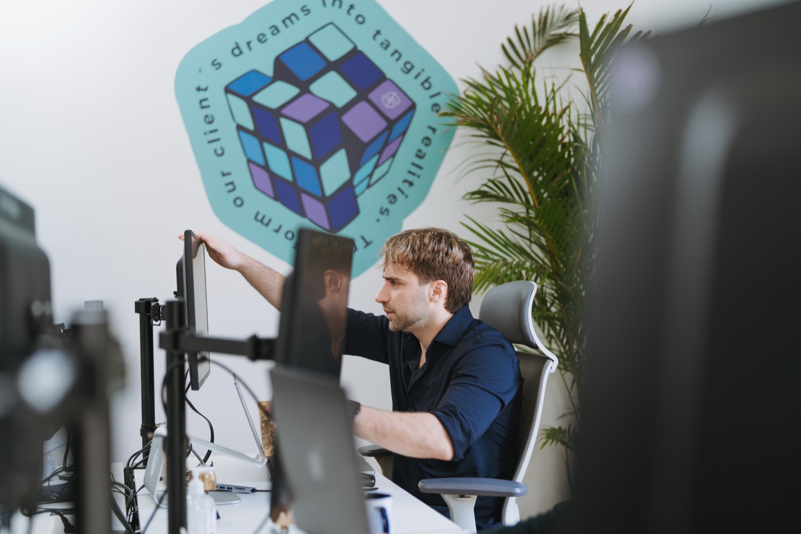 Somnio engineer adjusting a monitor at the office, in front of the Somnio cube mural