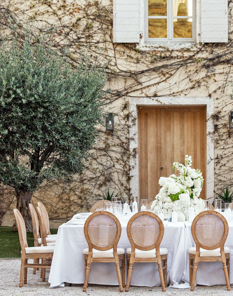 Une magnifique table de mariés avec nappe blanche, des fleurs et un olivier devant une vieille demeure, lors d'une prestation mariage en Provence en 2026.