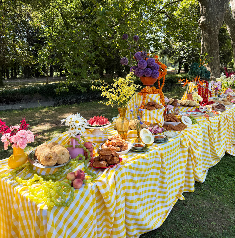 Une photo d'un brunch de mariage coloré en extérieur avec plein de plats et de fleurs.