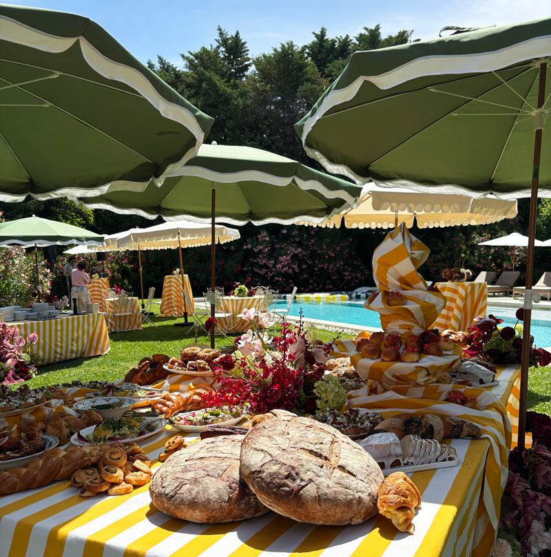 Grand buffet brunch installé au bord d’une piscine avec pains, viennoiseries et créations maison
