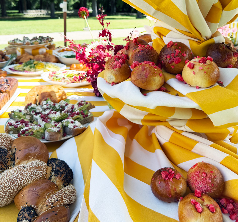 Pains et brioches maison présentés sur un buffet brunch coloré en plein air