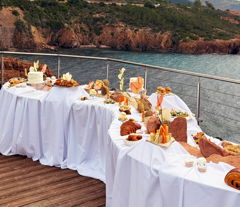 Buffet brunch dressé face à la mer avec viennoiseries, pains et créations salées à partager