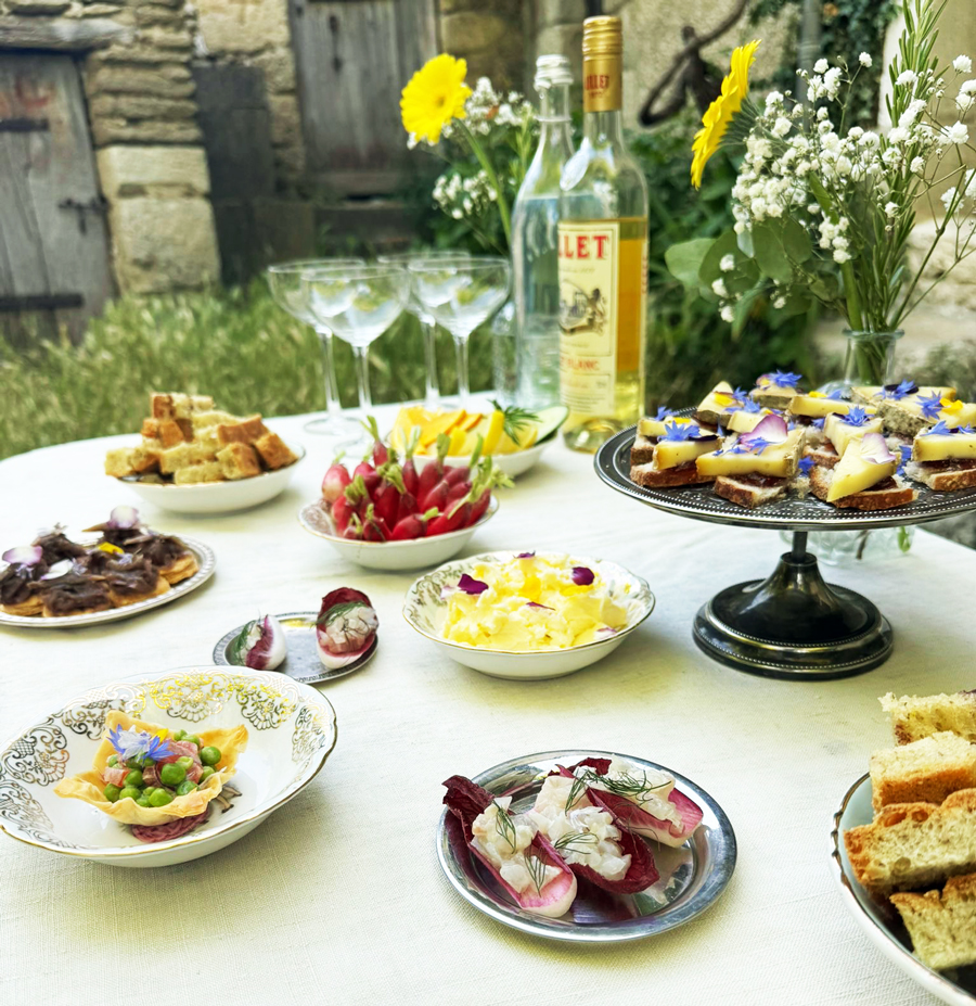 Buffet traiteur à domicile avec bouchées salées, légumes de saison et présentation florale en extérieur