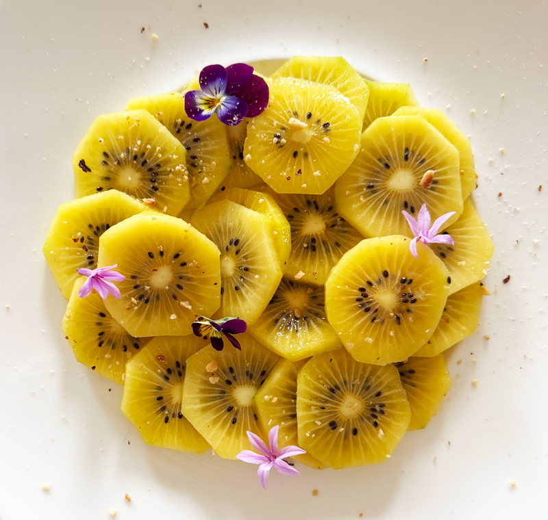 Assiette de kiwis frais décorée de fleurs comestibles pour un menu de chef à domicile