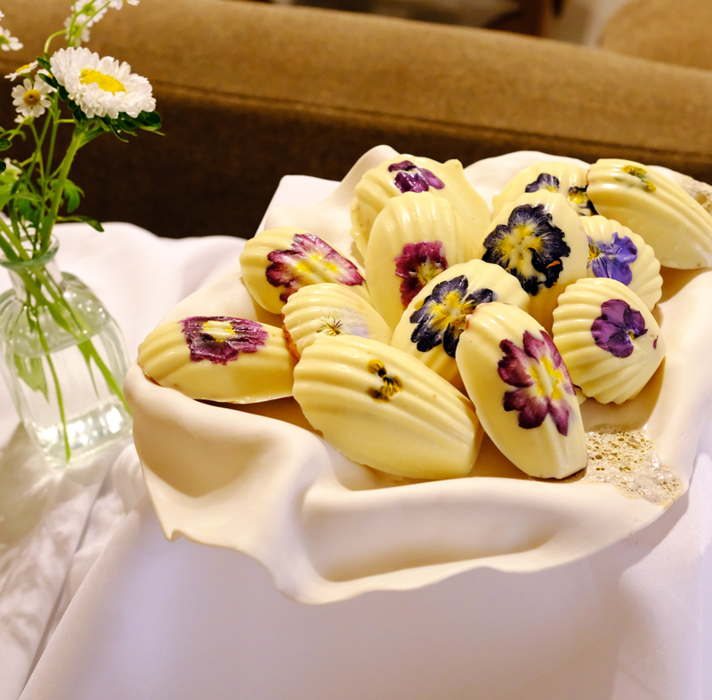 Madeleines décorées de fleurs comestibles pour un dessert de réception privée à domicile