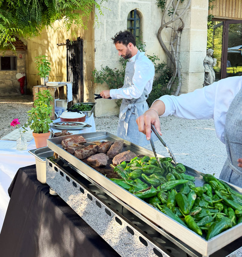 Chef cuisinant viandes et légumes à la plancha lors d’une réception privée à domicile