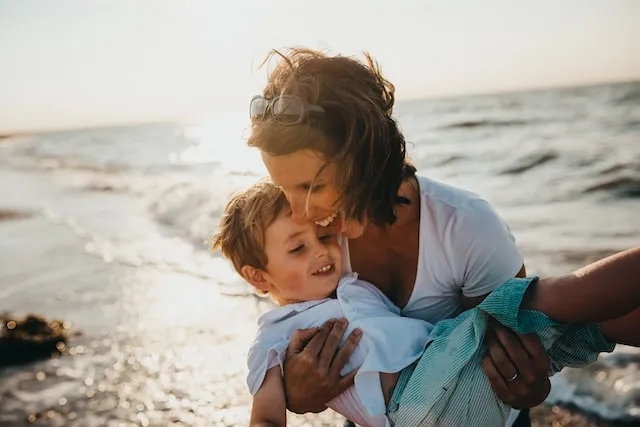 A mum holding her son on the beach
