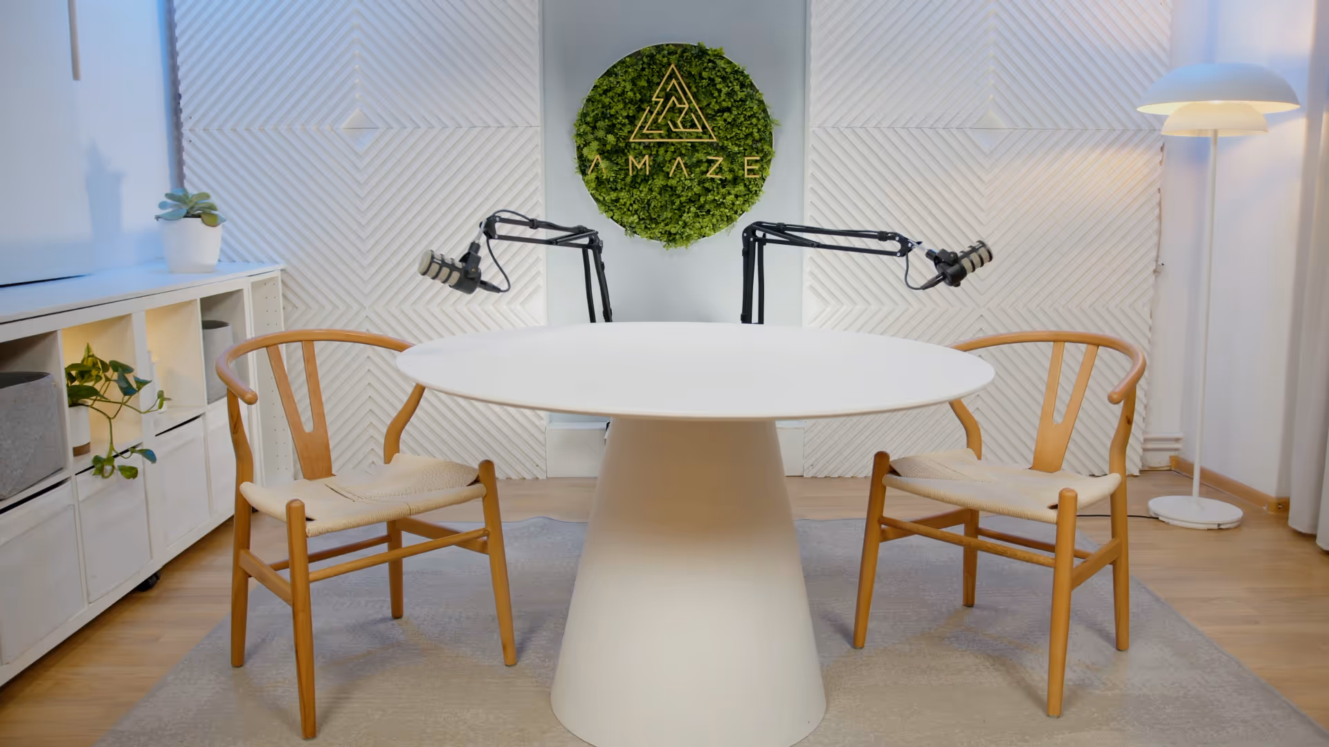 a table with two microphones and chairs in front of a green sign