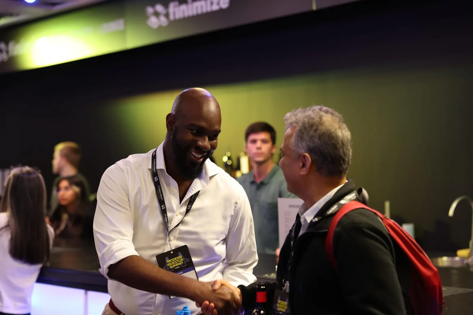 Two attendees shaking hands at the bar