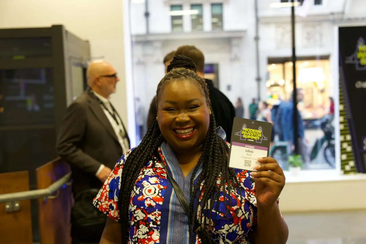 An attendee smiling and holding up her Summit badge