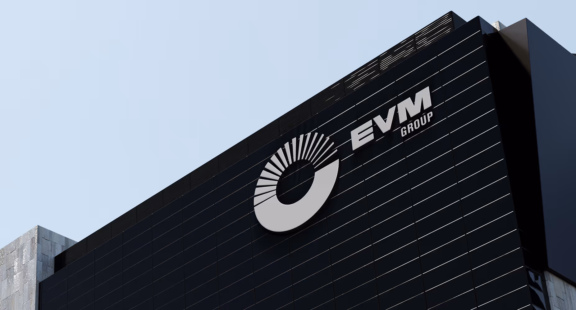 Modern black building facade with EVM Group logo in silver and a geometric circular design.