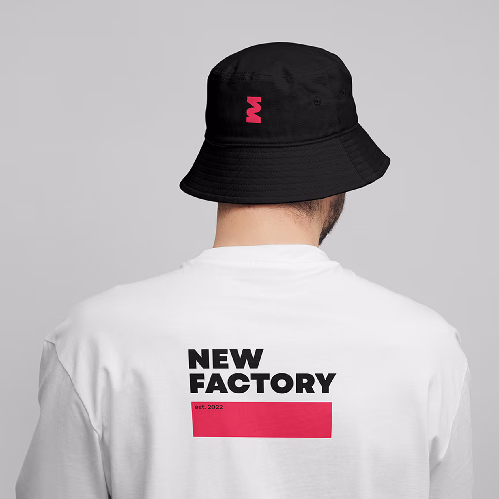 Person wearing black bucket hat and white shirt with 'NEW FACTORY est. 2022' printed on the back.