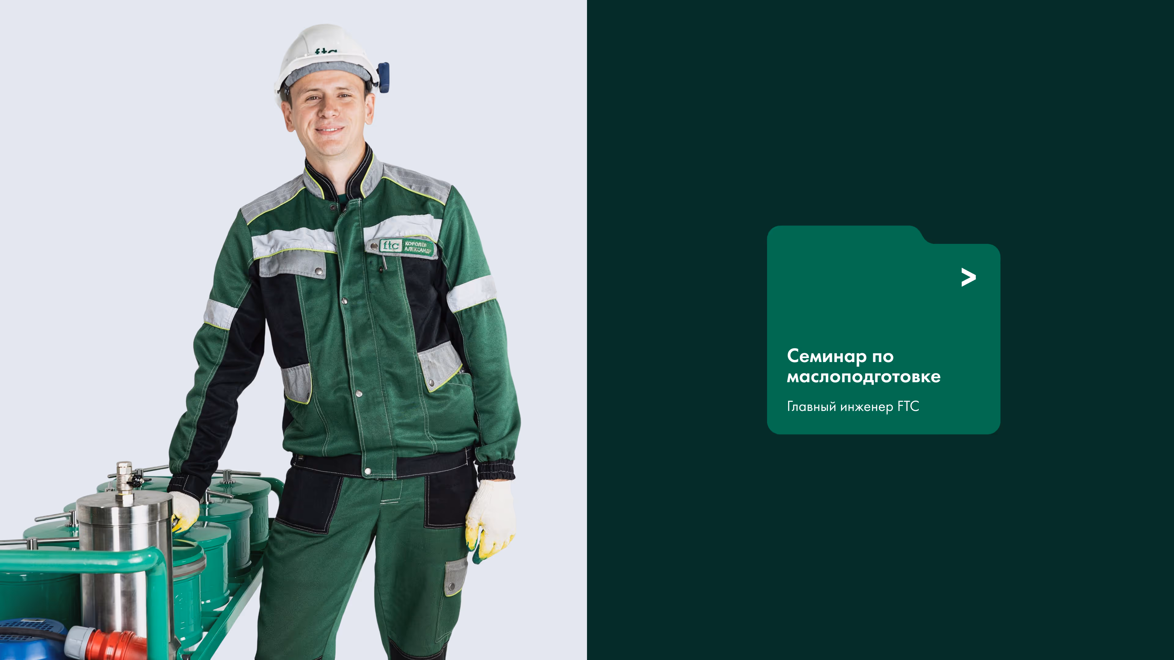 Smiling engineer in green uniform and helmet stands by industrial equipment against white and dark backgrounds.
