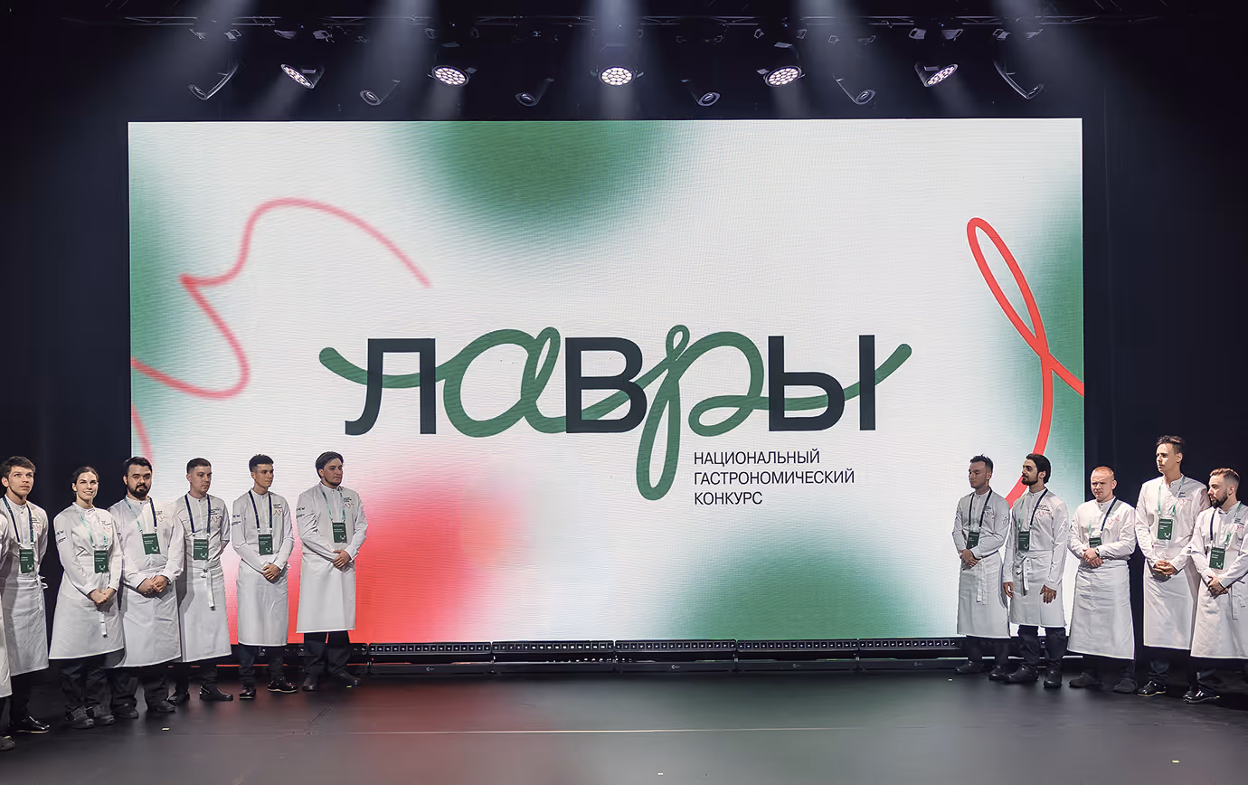 Group of chefs in white uniforms standing on stage in front of a large screen with Russian text.