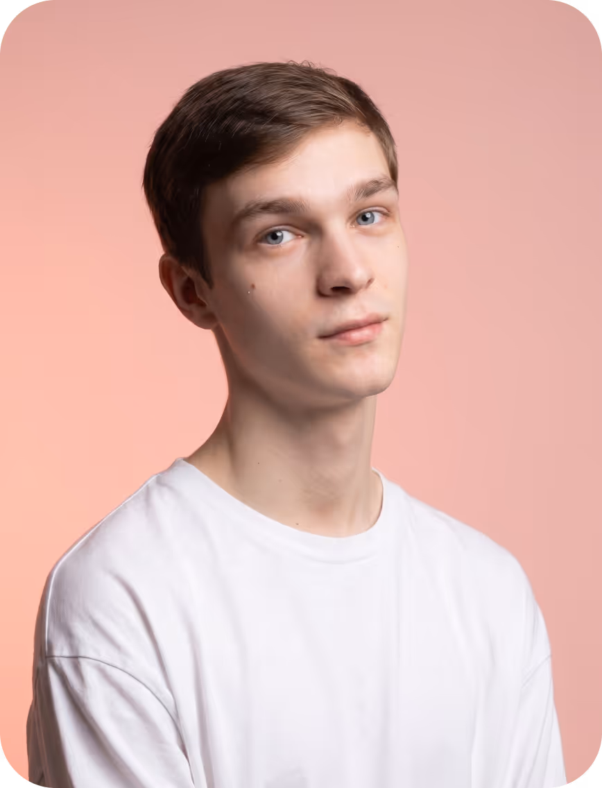 Young man with light brown hair wearing a white shirt against a pink background.
