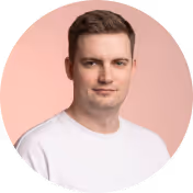 Portrait of a young man wearing a white shirt with a neutral expression on a pink background.