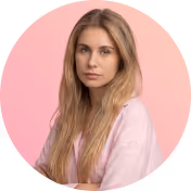 Portrait of a young woman with long blonde hair wearing a light pink shirt against a pink background.