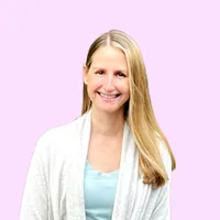 Smiling woman with long blonde hair wearing light blue top and white cardigan on pink background.