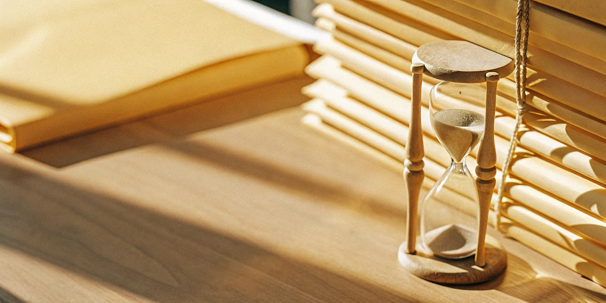 An hourglass and folders on a desk used for the aging of accounts receivable process.