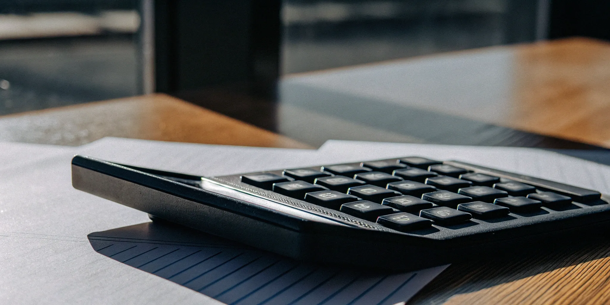 An annual recurring revenue calculator with financial documents on a desk.