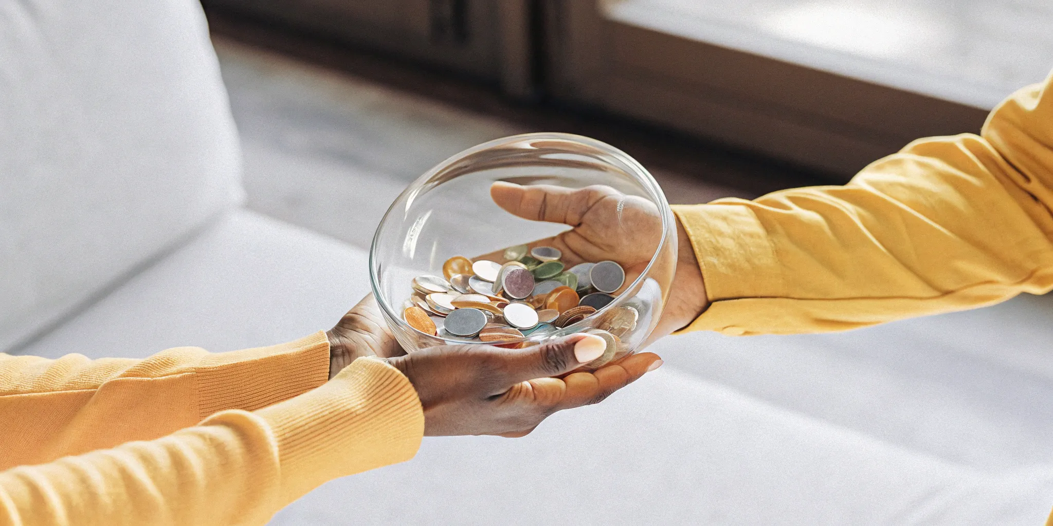Hands passing a bowl of coins, a clear example of revenue recognition.