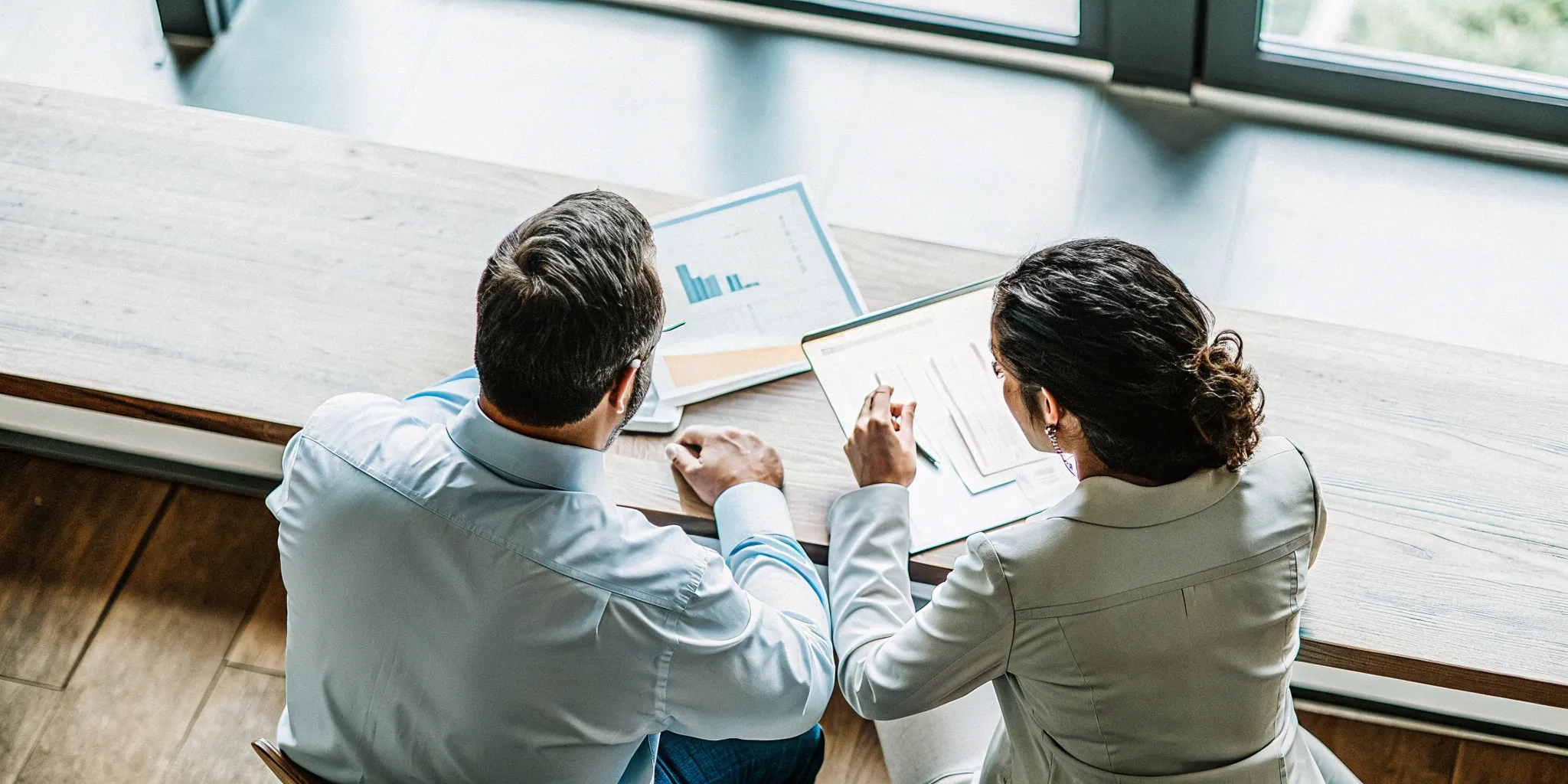 A finance business partner analyzes charts with a colleague to guide strategic decisions.