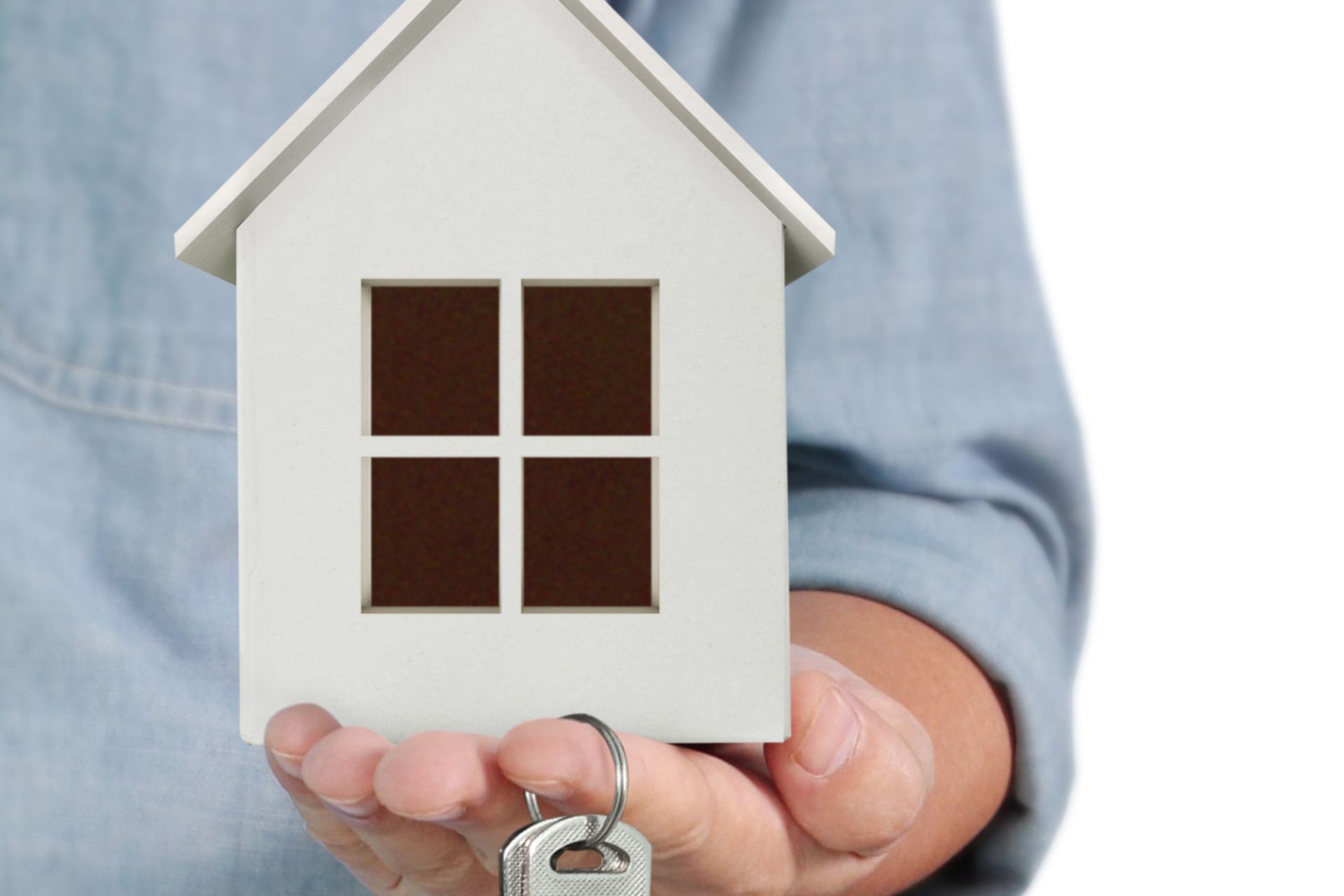 Persoon met houten huisje in de hand
