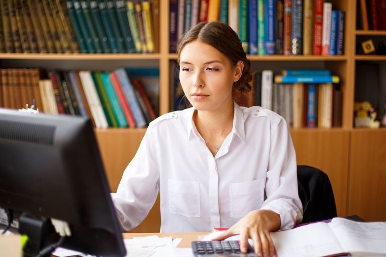 Vrouw achter pc met rekenmachine