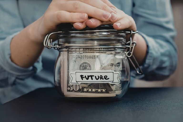Pot met geld waar ‘toekomst’ op staat met handen