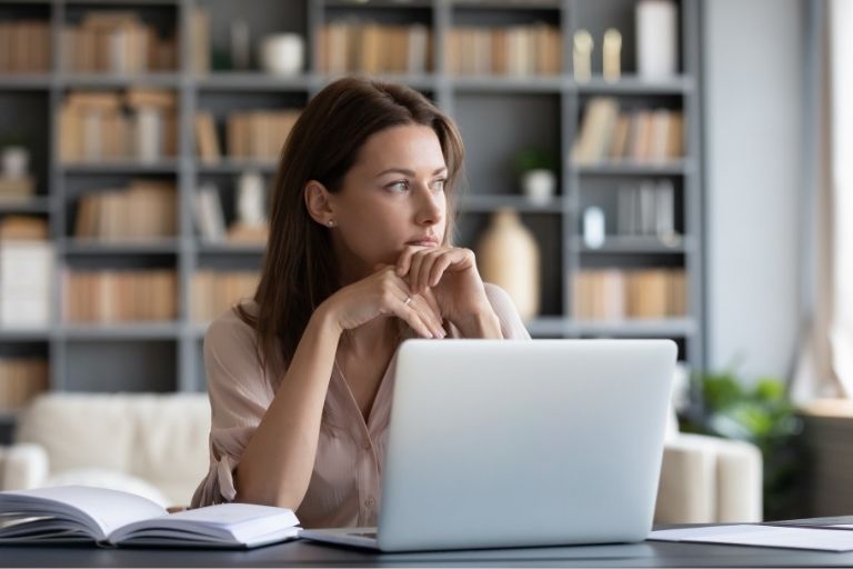 Vrouw denkend achter laptop