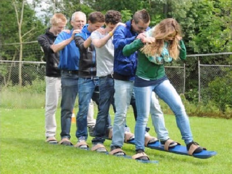 Zes personen hebben plezier op reuze ski's lopen door gras