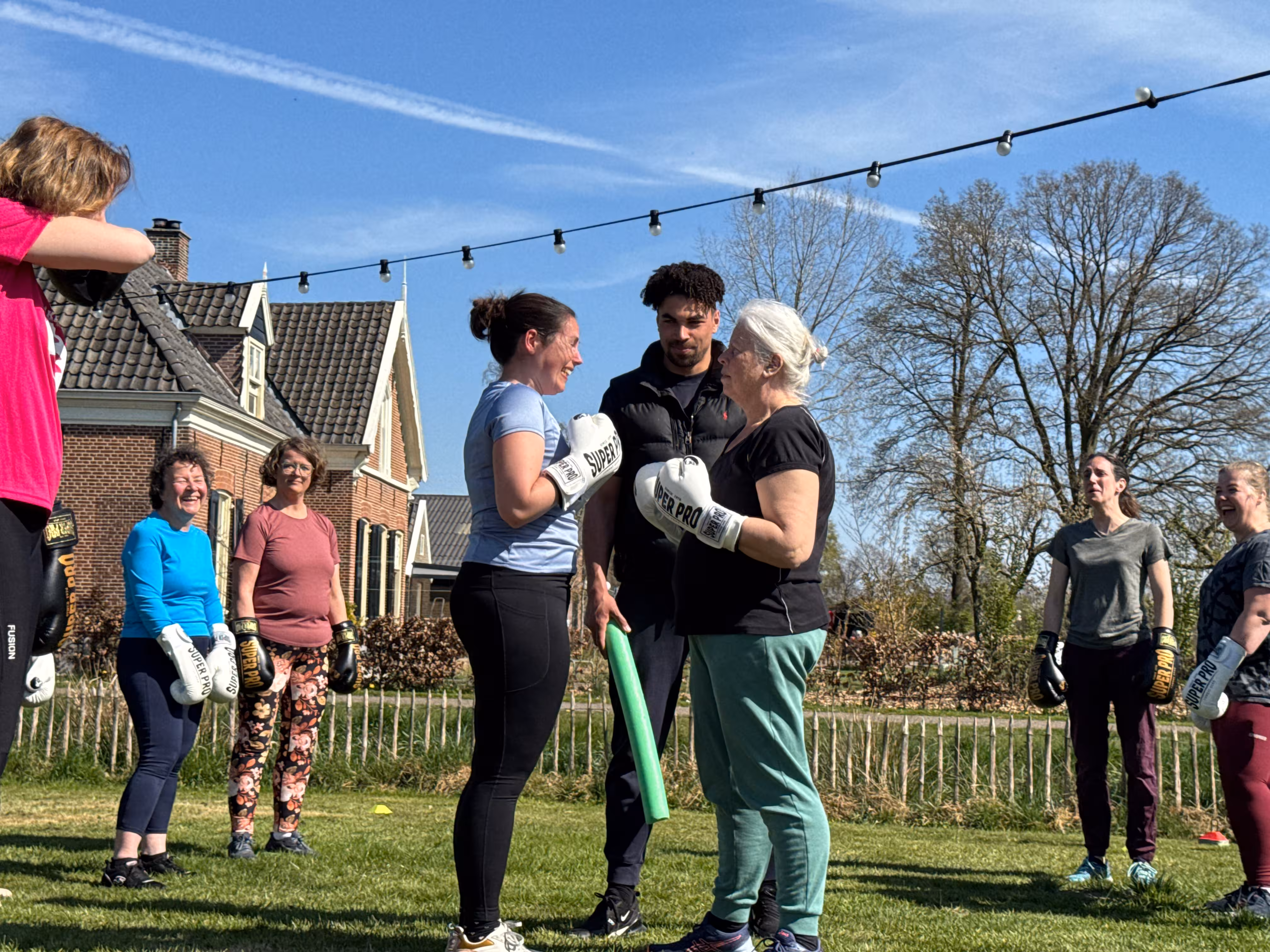 Twee vrouwen voeren een staredown uit, de boks instructeur staat tussen beide deelnemers