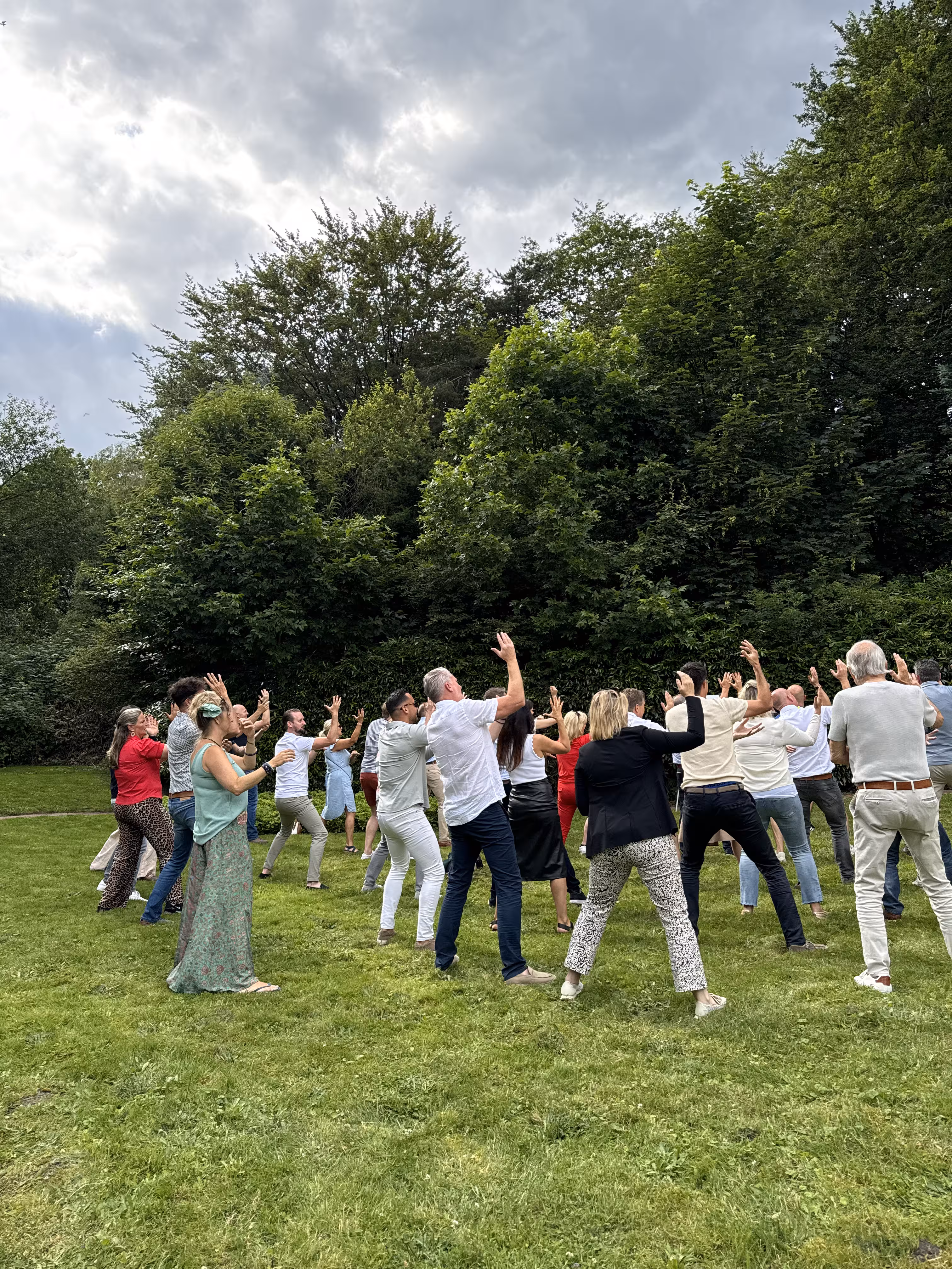 Er wordt een HAKA workshop verzorgd op een grasveld in een bosrijke omgeving
