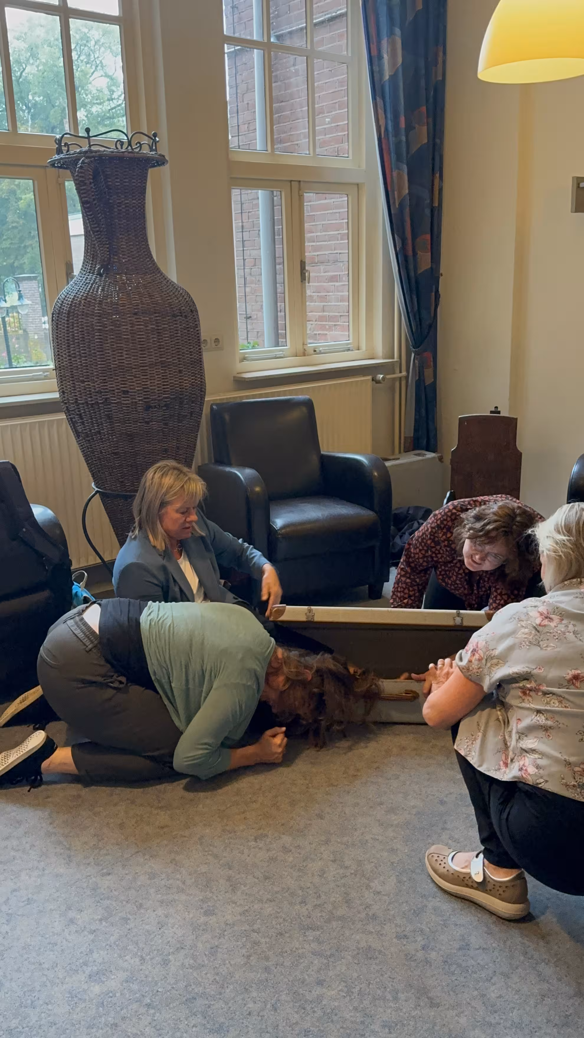 Een vrouw ligt bij een koffer en steekt daar haar arm in tijdens de workshop Het Perfecte Plaatje