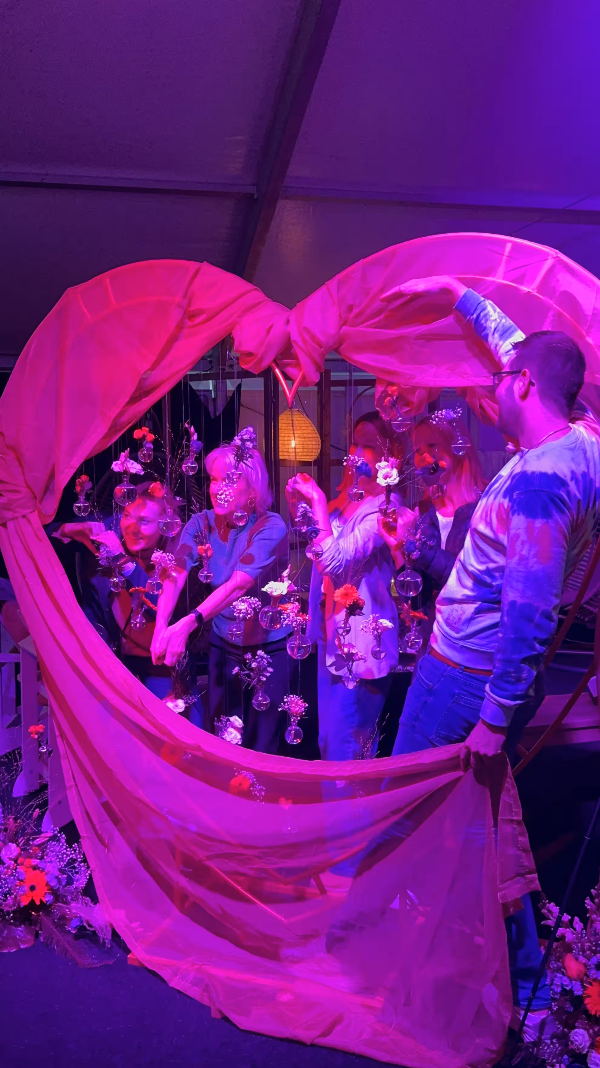 De groep staat tussen een hartvormige deken in een paarse belichte ruimte