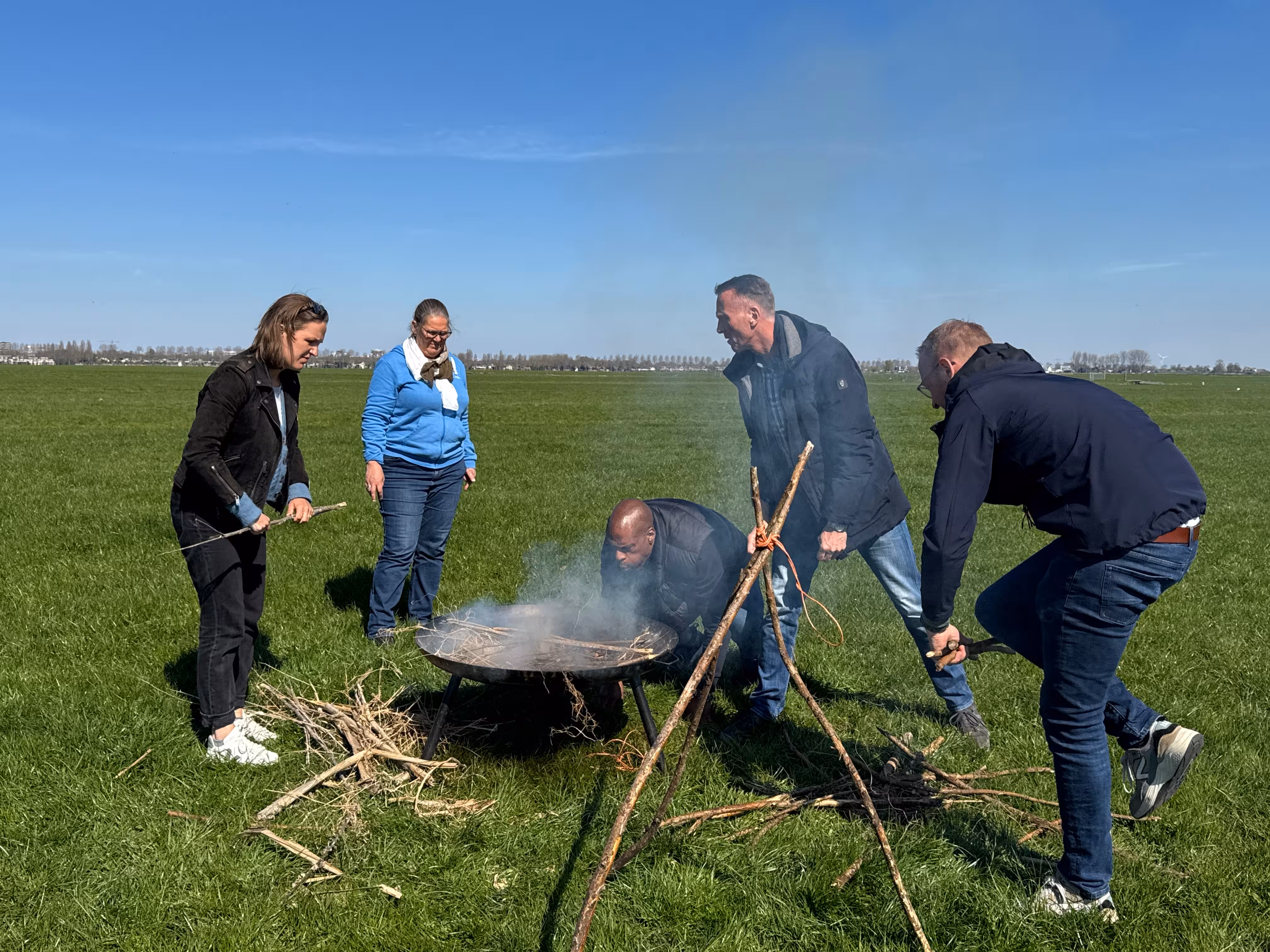 Er komt rook uit de vuurschaal en een man probeert het aan te krijgen door er in te blazen