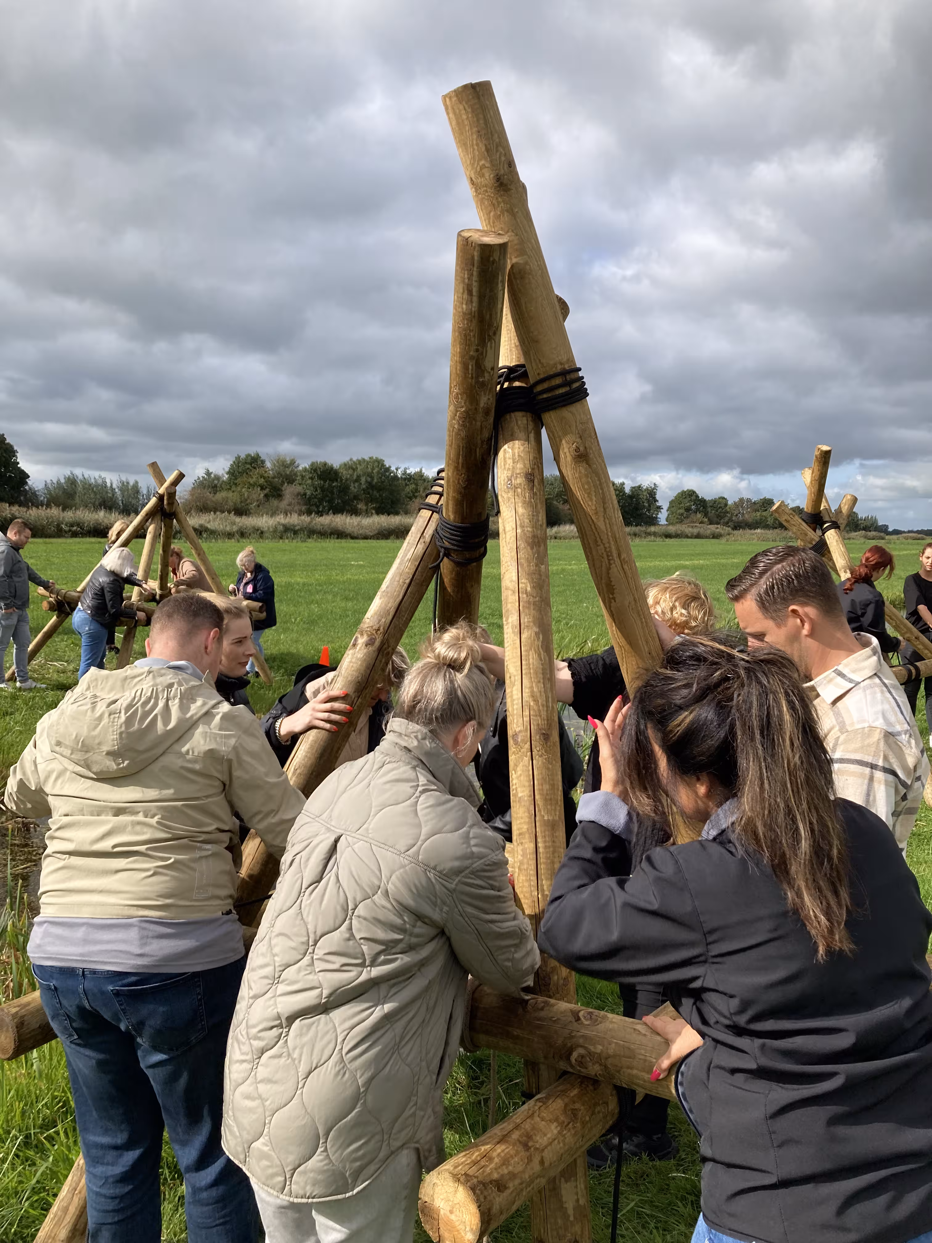 Er wordt een vierpoot gemaakt van houten balken en touw tijdens de activiteit brug bouwen