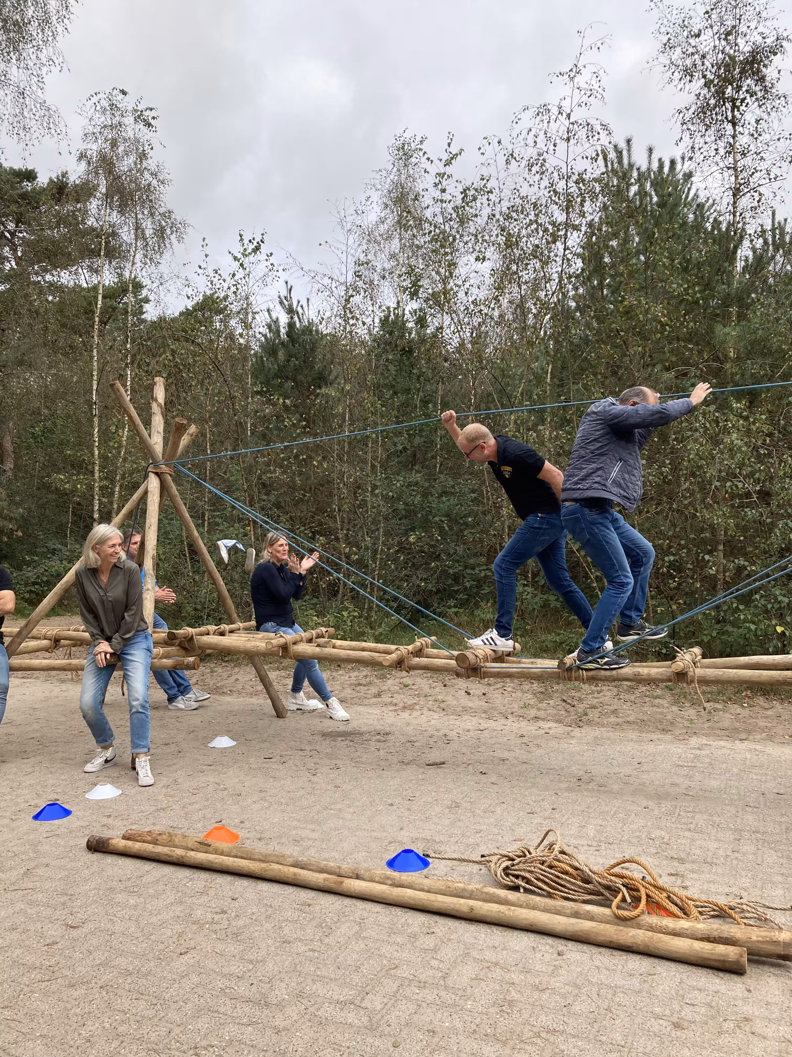 Op een verharde ondergrond is een brug gebouwd en twee mannen lopen er overheen