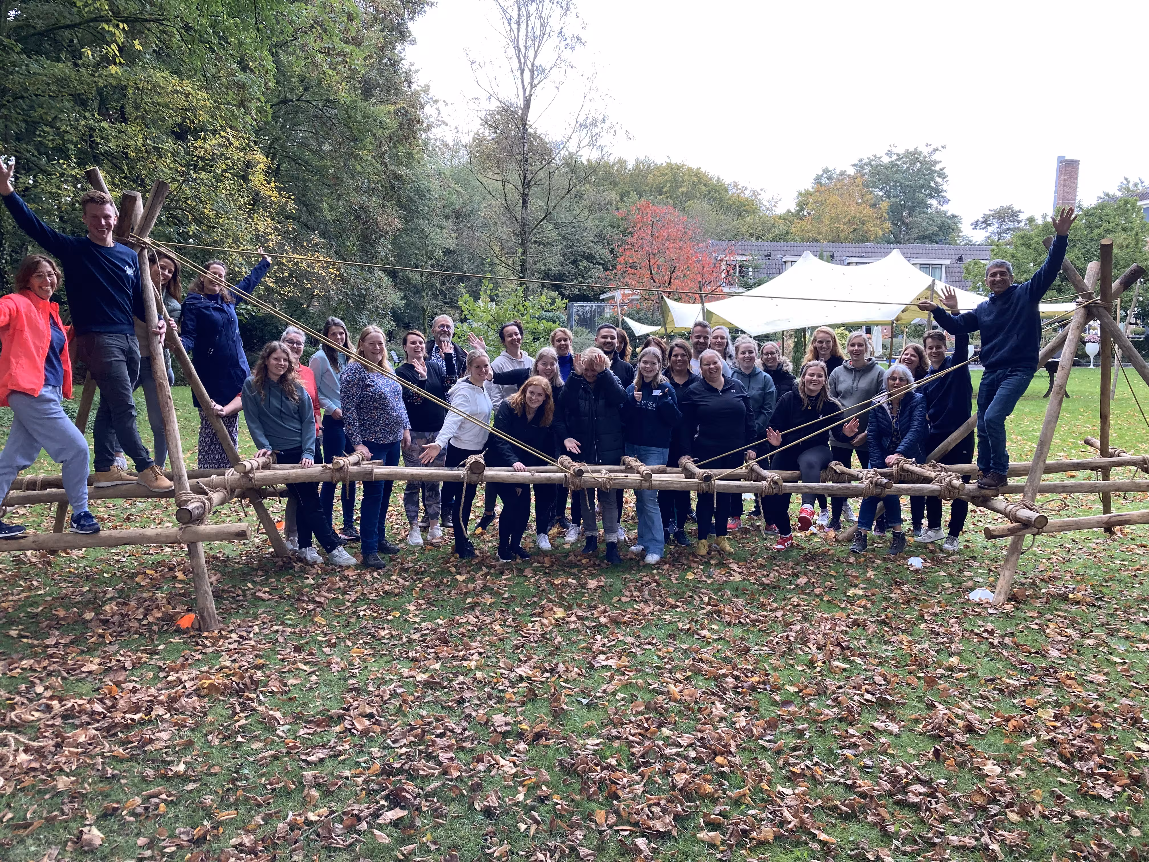 Er is een brug gebouwd met touwen en houten balken en de groep poseert bij de brug
