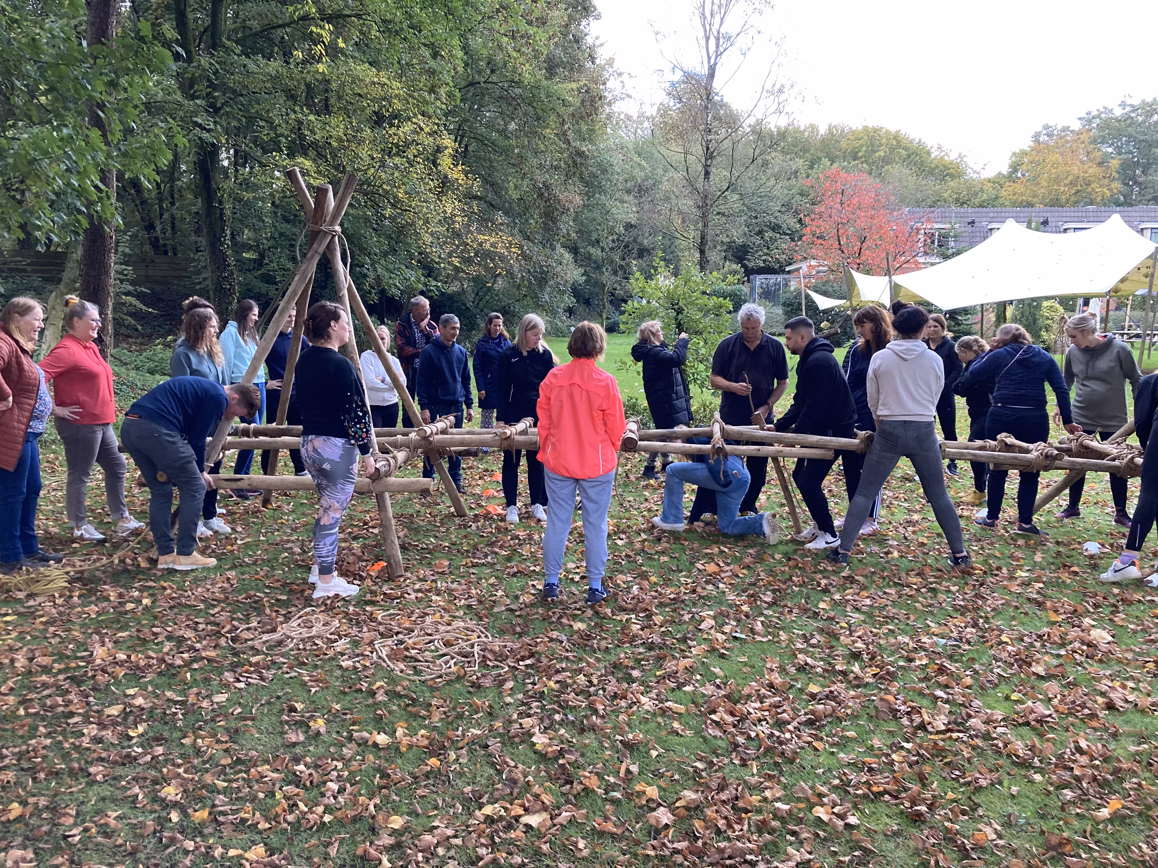 Op een grasveld staan de deelnemers om de zelfgemaakte brug heen