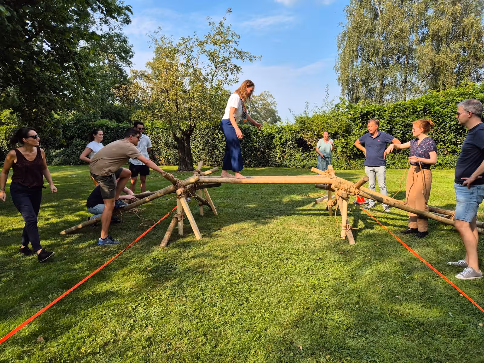 Een vrouw loopt over een zelfgemaakte brug van hout en touwen en probeert haar evenwicht te houden