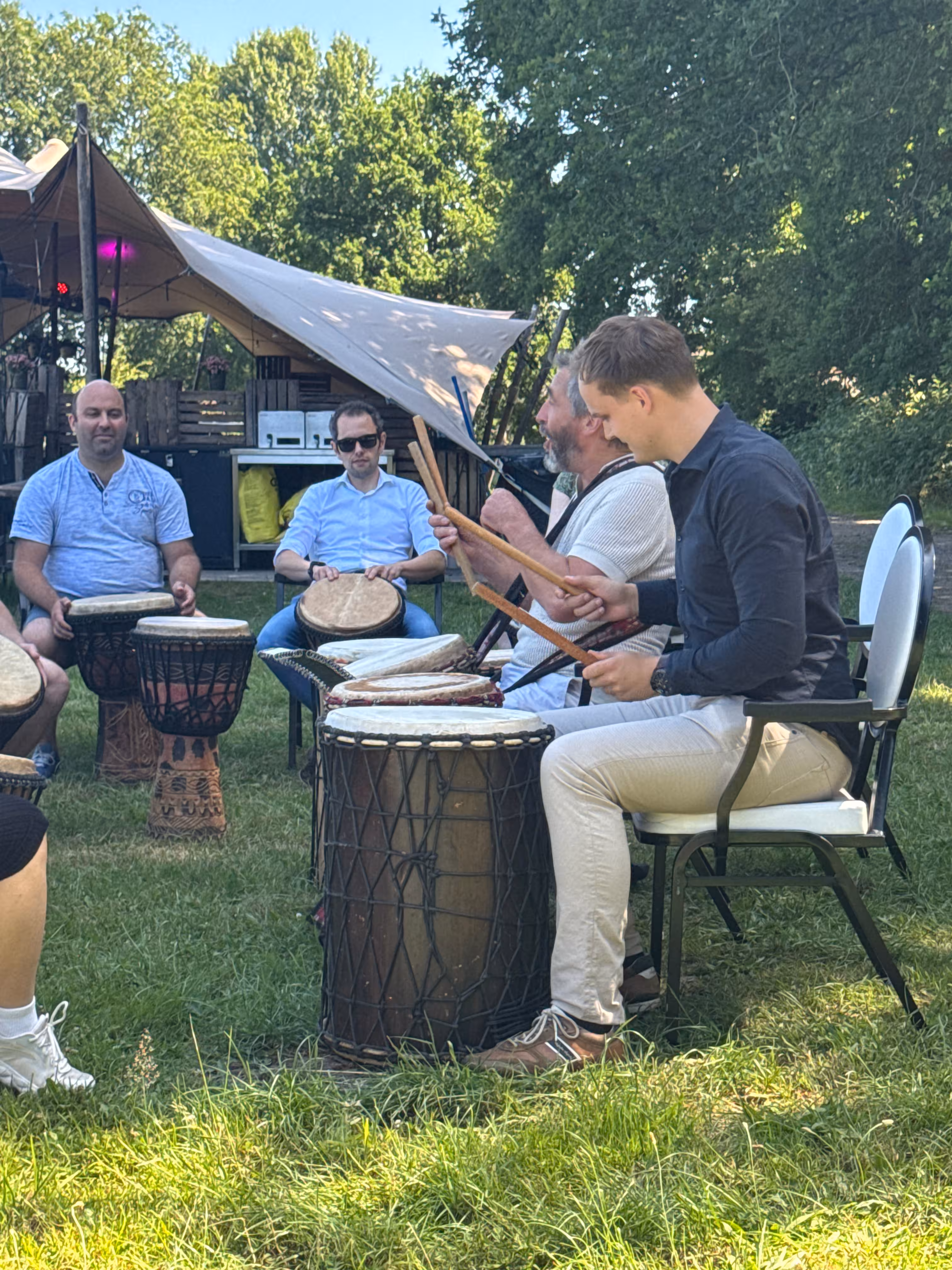De deelnemers slaan met stokken op de trommels tijdens de Percussie workshop verzorgd door BuitenEvents